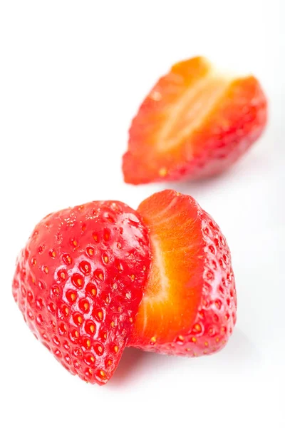 Red fresh strawberries cut into half arranged on a white background. — Stock Photo, Image