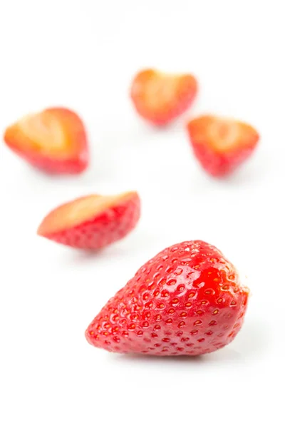 Red fresh cut and whole strawberries arranged on a white background. — Stock Photo, Image