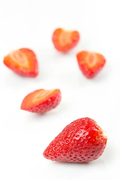 Red fresh cut and whole strawberries arranged on a white background. — Stock Photo, Image