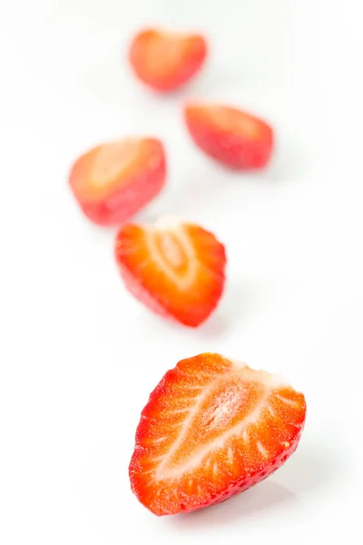 Red fresh strawberries cut into half arranged on a white background. — Stock Photo, Image