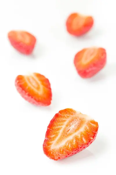 Red fresh strawberries cut into half arranged on a white background — Stock Photo, Image