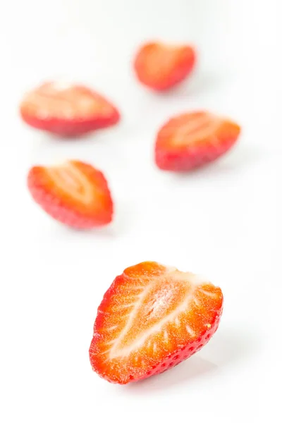 Red fresh strawberries cut into half arranged on a white background — Stock Photo, Image