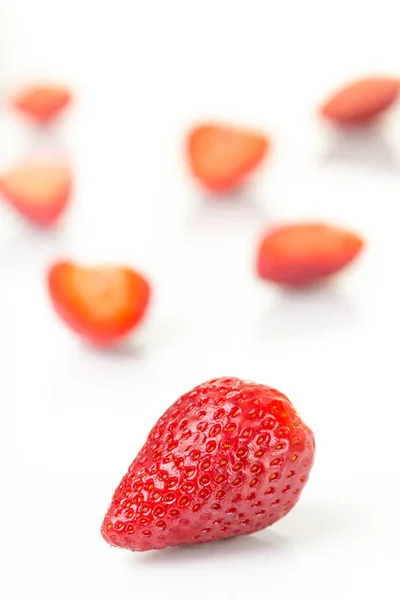 Fresas rojas frescas cortadas y enteras dispuestas sobre un fondo blanco . — Foto de Stock