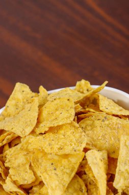 Tahta masada beyaz kasede sarı nacho.
