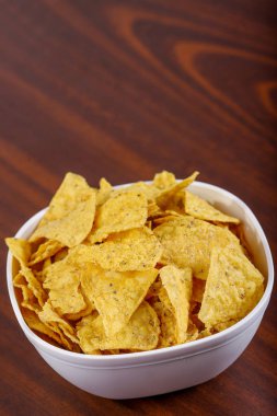 Tahta masada beyaz kasede sarı nacho.