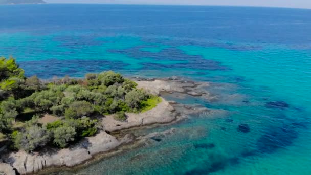 光の反射と岩の海岸の青い海面の航空写真 透明なターコイズブルーの海水面と海岸の岩のトップビュー — ストック動画