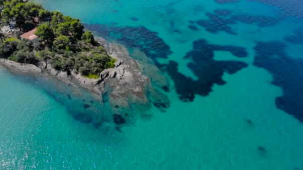 光の反射と岩の海岸の青い海面の航空写真 透明なターコイズブルーの海水面と海岸の岩のトップビュー — ストック動画