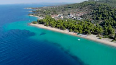Ağaçlarla çevrili kumlu plajda mavi deniz yüzeyinin havadan drone görünümü. Şeffaf turkuaz okyanus su yüzeyi, deniz kıyısı, orman üst görünümü.