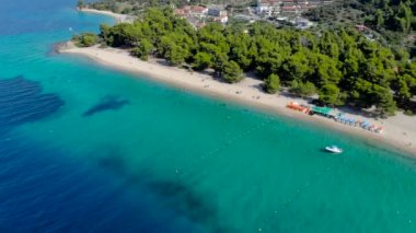 Ağaçlarla çevrili kumlu plajda mavi deniz yüzeyinin havadan drone görünümü. Şeffaf turkuaz okyanus su yüzeyi, deniz kıyısı, orman üst görünümü.