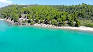 Ağaçlarla çevrili kumlu plajda mavi deniz yüzeyinin havadan drone görünümü. Şeffaf turkuaz okyanus su yüzeyi, deniz kıyısı, orman üst görünümü.