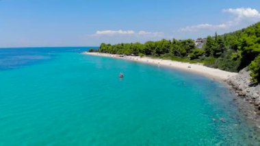 Ağaçlarla çevrili kumlu plajda mavi deniz yüzeyinin havadan drone görünümü. Şeffaf turkuaz okyanus su yüzeyi, deniz kıyısı, orman üst görünümü.