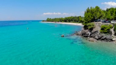 Ağaçlarla çevrili kumlu plajda mavi deniz yüzeyinin havadan drone görünümü. Şeffaf turkuaz okyanus su yüzeyi, deniz kıyısı, orman üst görünümü.