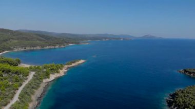 Ağaçlarla çevrili mavi deniz yüzeyinin havadan drone görünümü. Koyu mavi okyanus su yüzeyi, deniz kıyısı, orman, araba yolu üst görünümü.