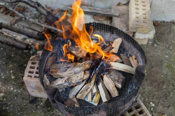 Wood fire for barbecue in black metal container.