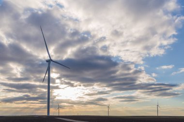 Arka planda bulutlu gökyüzü ile tarımsal zeminde Rüzgar türbinleri