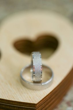 Kalp şeklinde ahşap kasa üzerinde iki alyans. Gümüş yüzük makro çekim kapatın