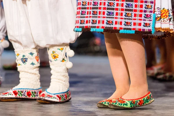 Blízko nohou mladých rumunských tanečníků se v tradičním folklorním kostýmu provádí folkový tanec. Folklór Rumunska — Stock fotografie