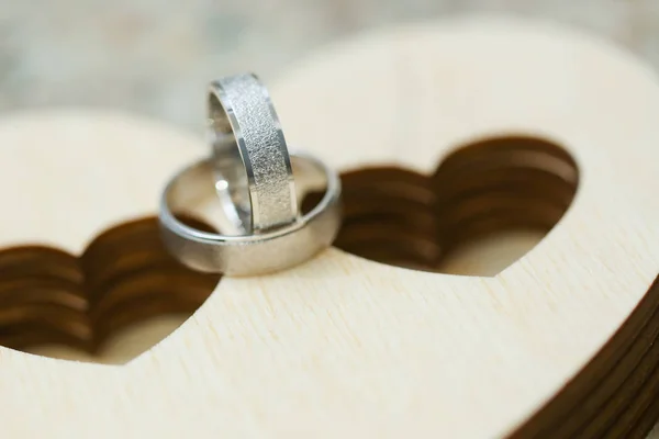 Twee trouwringen op houten geval in hart vorm. Close-up macro-opname van zilveren ringen — Stockfoto