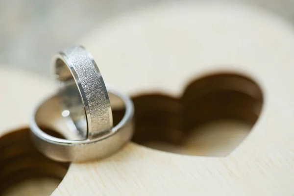 Dois anéis de casamento em caixa de madeira em forma de coração. Fechar macro tiro de anéis de prata — Fotografia de Stock