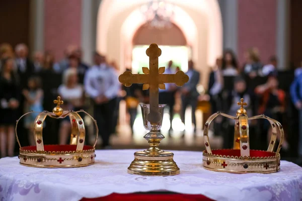 Dos coronas y cruz sobre mesa blanca preparada para la boda. Iglesia ortodoxa accesorios de boda . — Foto de Stock