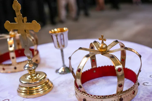 Dos coronas y cruz sobre mesa blanca preparada para la boda. Iglesia ortodoxa accesorios de boda . — Foto de Stock