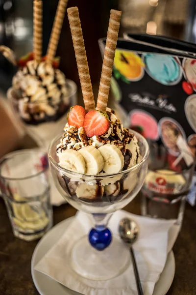 Ice cream cup with three pieces of banana and two pieces of strawberry on table with blurred background