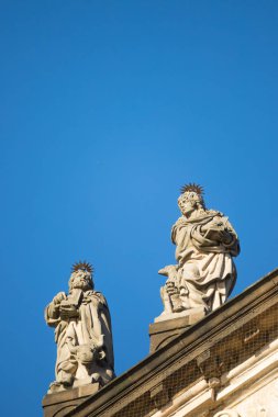 Arka planda mavi gökyüzü ile Prag'da Assisi kilisesinin St Francis çatısında Heykeller