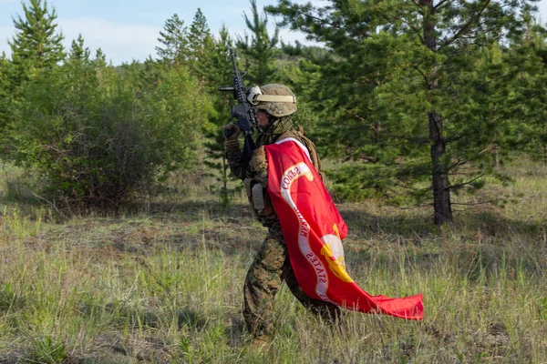 Vollbewaffneter amerikanischer Soldat mit Flagge des US Marine Corps im Sommerwald, aktives militärisches Spiel Airsoft. — Stockfoto