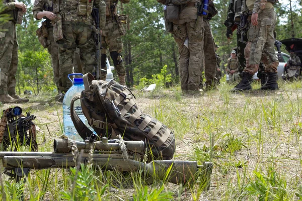 Drei Gewehre, Rucksack und Wasserflasche auf dem Boden im Wald, Armeewaffe des aktiven militärischen Spiels Airsoft — Stockfoto