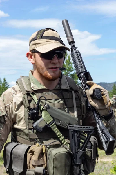 Vollbewaffneter amerikanischer Soldat im Sommerwald auf militärischem Gelände, aktives militärisches Spiel airsoft, vertikales Bild. — Stockfoto