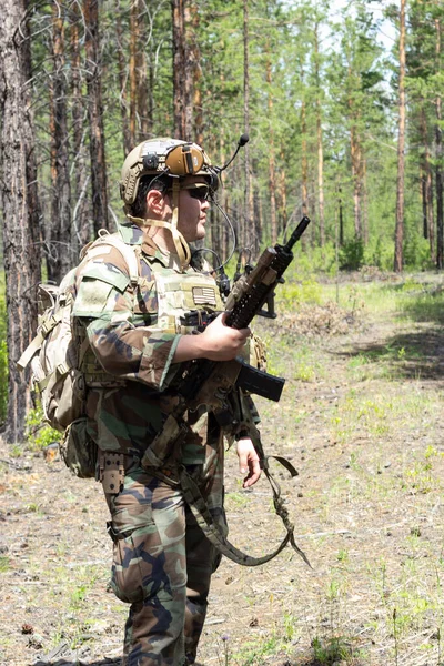 Vollbewaffneter amerikanischer Soldat im Sommerwald auf militärischem Gelände, aktives militärisches Spiel airsoft, vertikales Bild. — Stockfoto