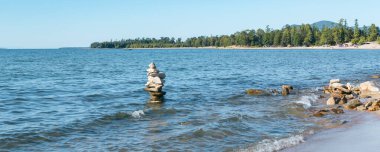 Yığılmış taşlar piramidi Baykal Gölü dalgaları, manzaralı deniz manzarası, istikrar ve denge konsepti, pankart ile yıkanır.