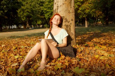 parkta bir ağacın altında oturan bir bayan