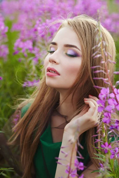 Attraktiva flicka i ett fält med blommor — Stockfoto