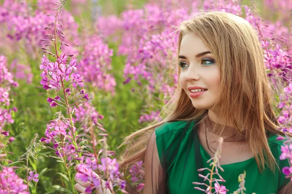 Menina atraente em um campo com flores — Fotografia de Stock