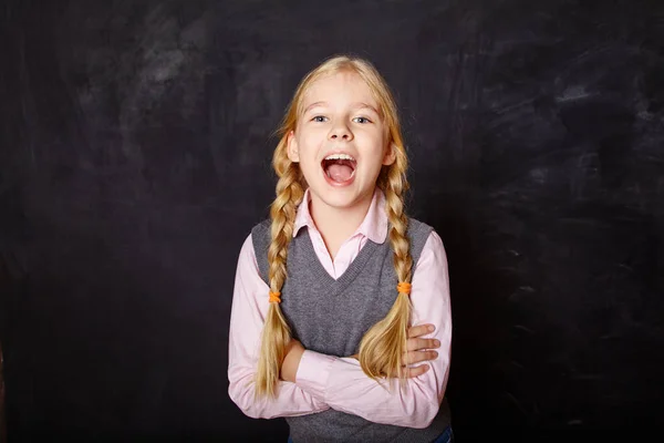 Grappige schoolmeisje op schoolbord achtergrond — Stockfoto