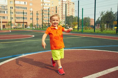 komik küçük çocuk oyun üzerinde. Çocuk spor zemin üzerinde oynama