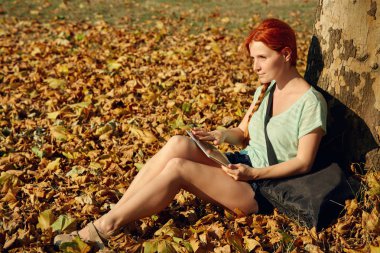 parkta bir ağacın altında oturan bir bayan