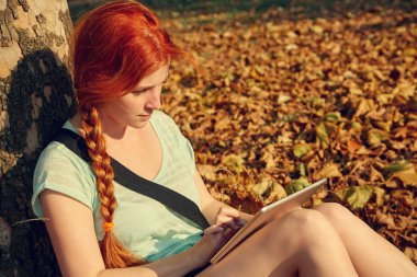 parkta bir ağacın altında oturan bir bayan