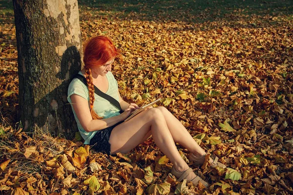 Жінка сидить під деревом в парку — стокове фото