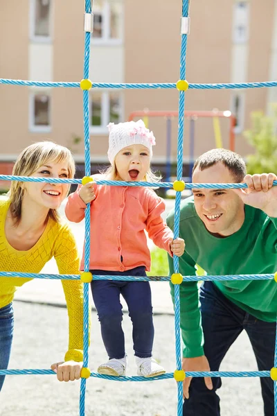 Kind met ouders op een speelplaats — Stockfoto