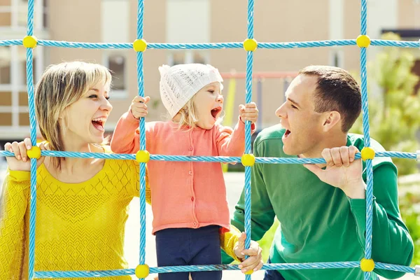 Дитина з батьками на дитячому майданчику — стокове фото