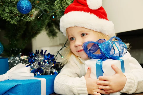 Kleines Mädchen mit Weihnachtsmütze und Geschenk — Stockfoto