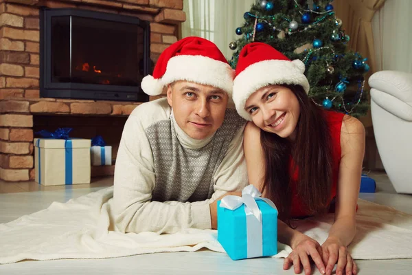 Jeune couple avec une boîte cadeau sur le fond de l'arbre de Noël — Photo