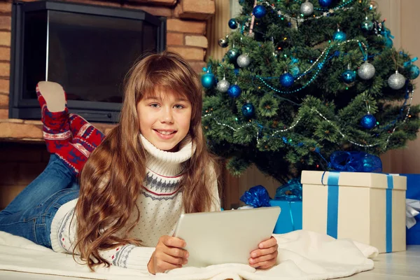 Glückliches Teenager-Mädchen mit Tablet-Computer in der Nähe des Weihnachtsbaums — Stockfoto