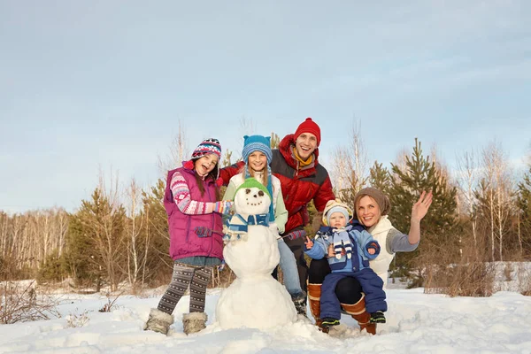 Porträt einer Familie mit Schneemann. Glückliche Kinder und Eltern im Winter im Freien — Stockfoto