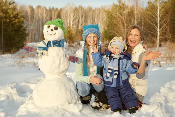 Porträt einer Familie mit Schneemann. Glückliche Kinder und Eltern im Winter im Freien — Stockfoto