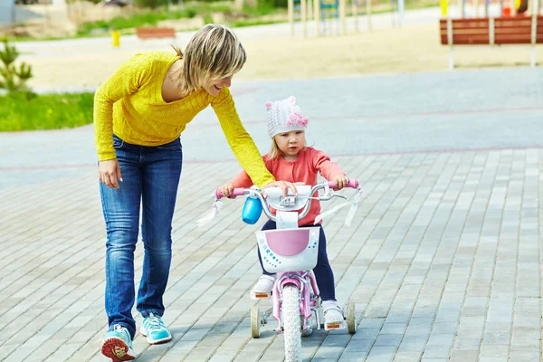 Маленька дівчинка з матір'ю їде на велосипеді — стокове фото