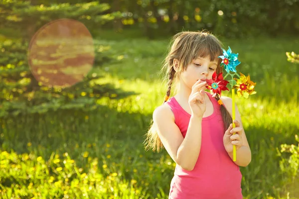 Alegre niña jugando con molinete en el parque de verano —  Fotos de Stock