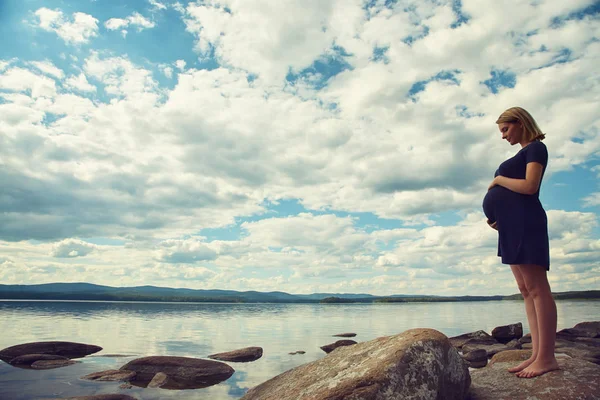 Aktiv, ung, gravid kvinne på land ved en innsjø – stockfoto